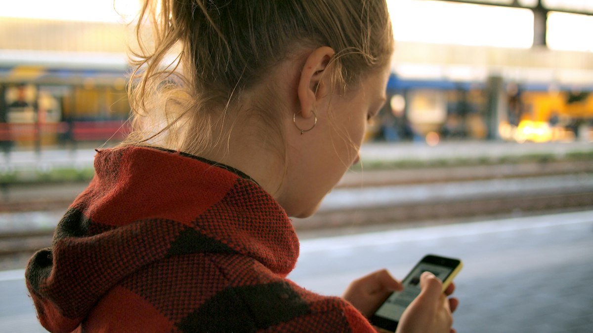 Woman checking her phone on a station platform