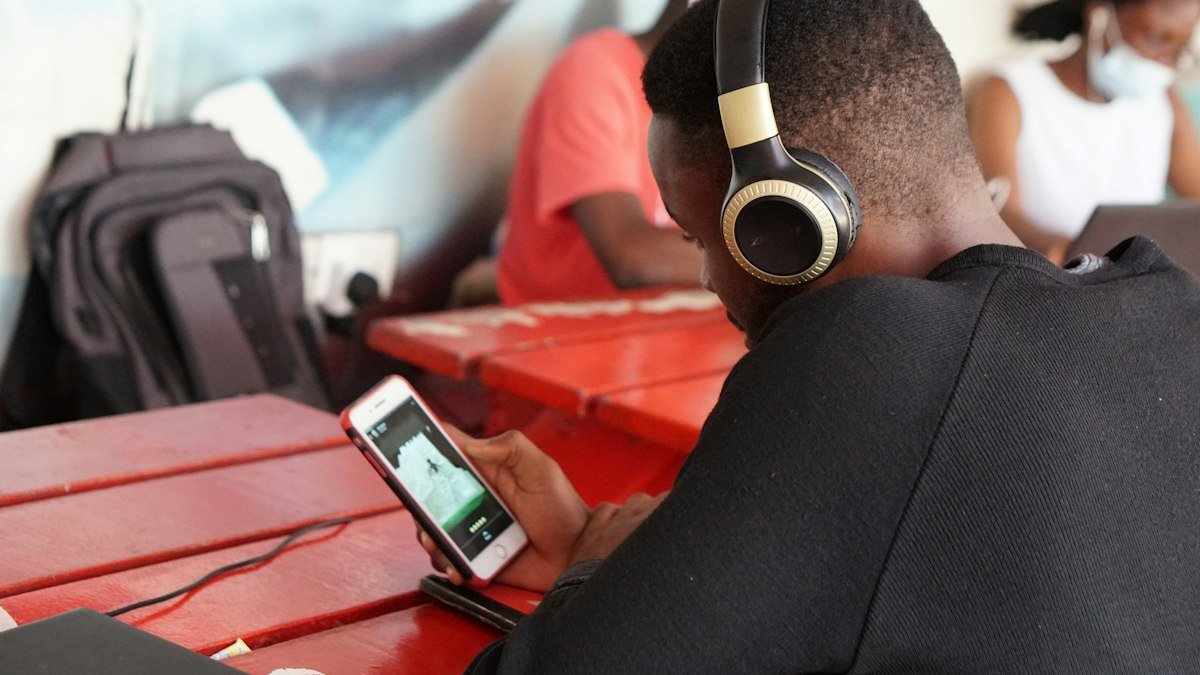 Student in headphones using his phone at a table