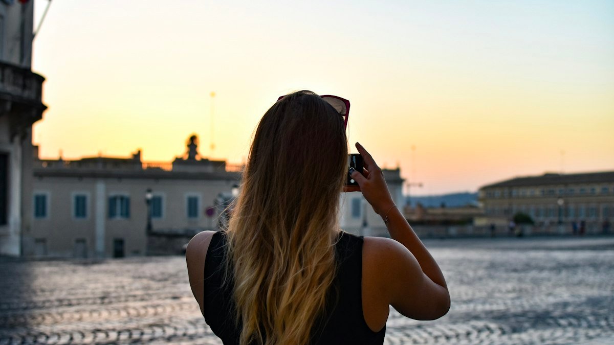 Traveller taking a photo with a smartphone in a European square at sunset